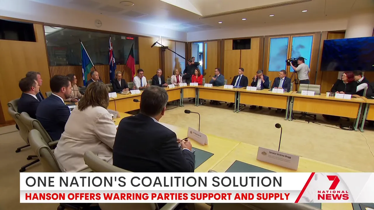 Wide-angle view of a long conference table with delegates seated around it and media present in the room.