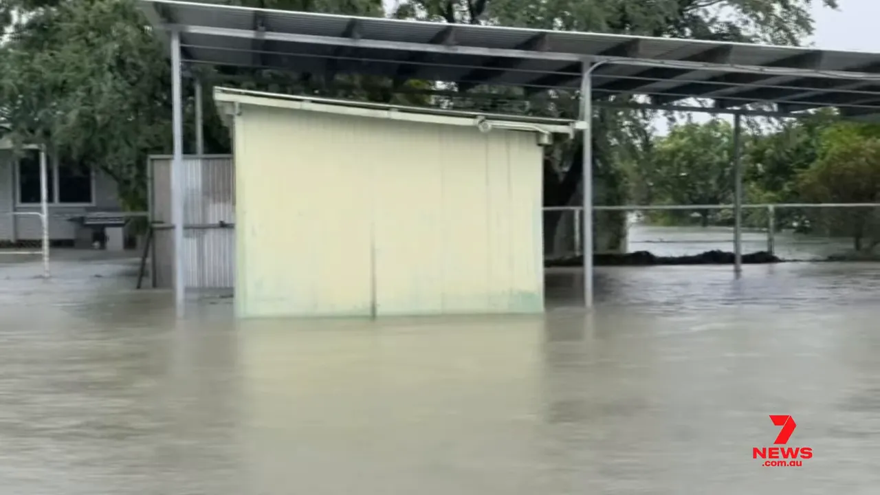 Floodwaters around an outbuilding and fence, illustrating flooded property and submerged yards