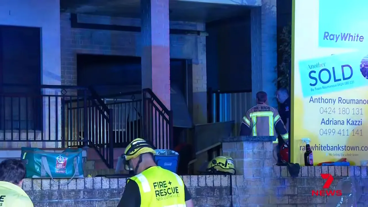 Front of the targeted residence with a Ray White 'SOLD' sign, firefighters and equipment at the entrance