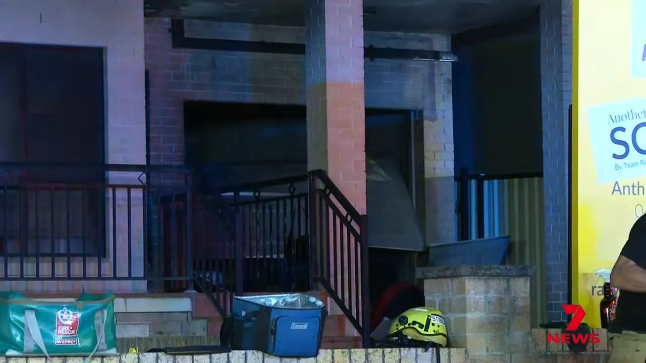 Damaged garage roller door and entrance at Greenacre home with firefighter equipment in foreground