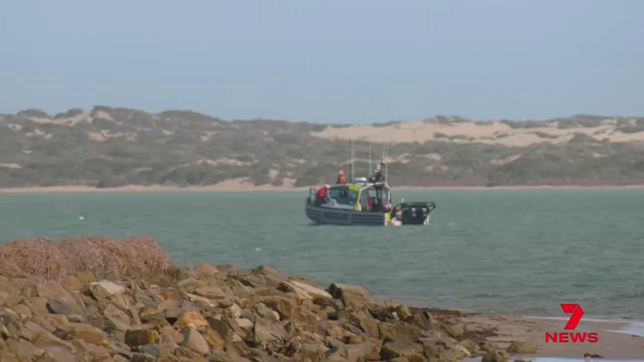 Rescue boat conducting search operations offshore near rocky shoreline