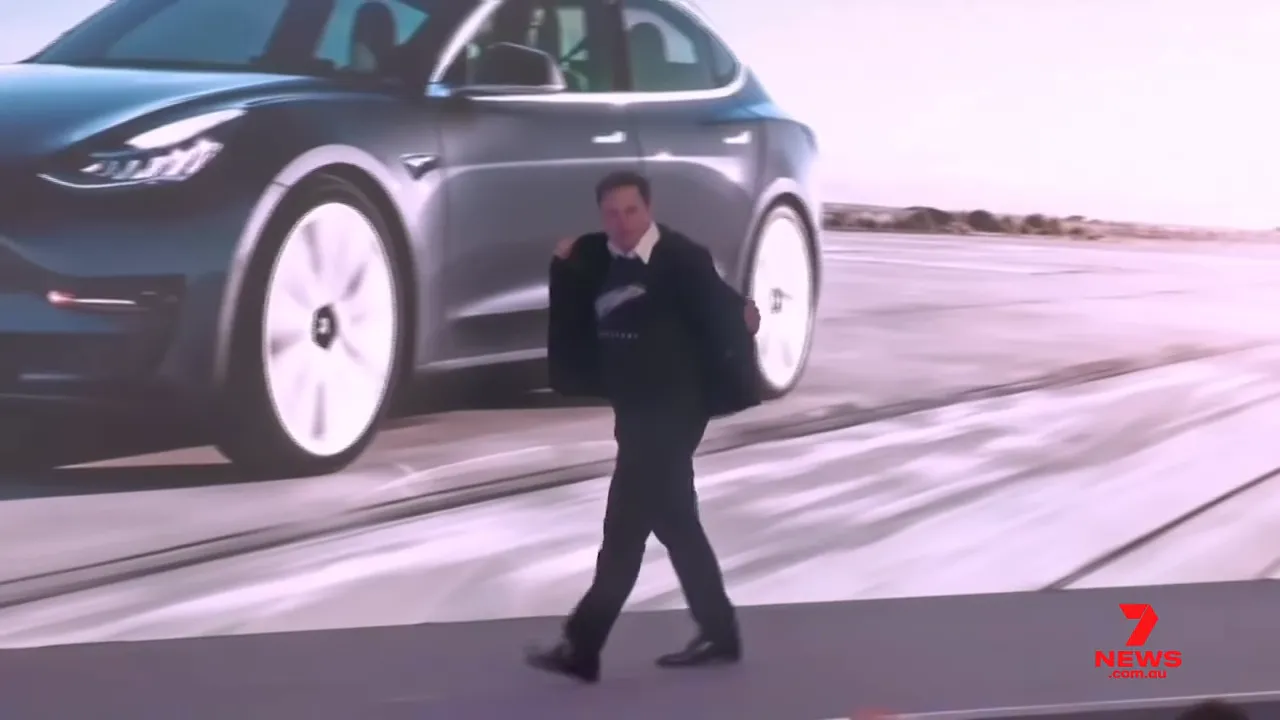 Executive walking onstage in front of a large display image of an electric car