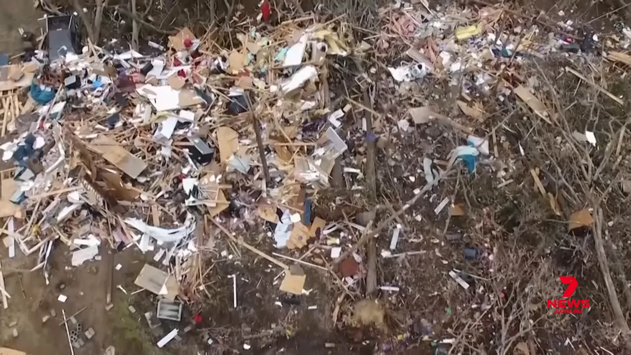 Close aerial photo showing timber, household debris and downed trees scattered across a property after a tornado