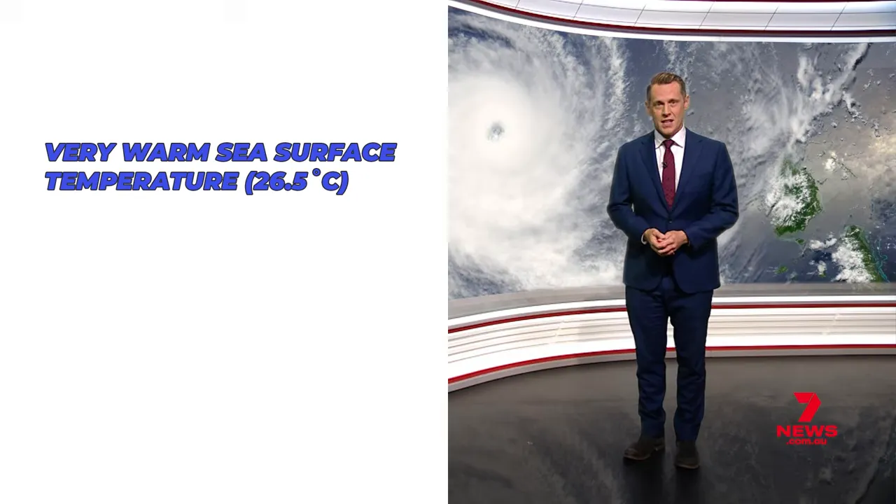 presenter standing in front of satellite image of a cyclone with a visible eye
