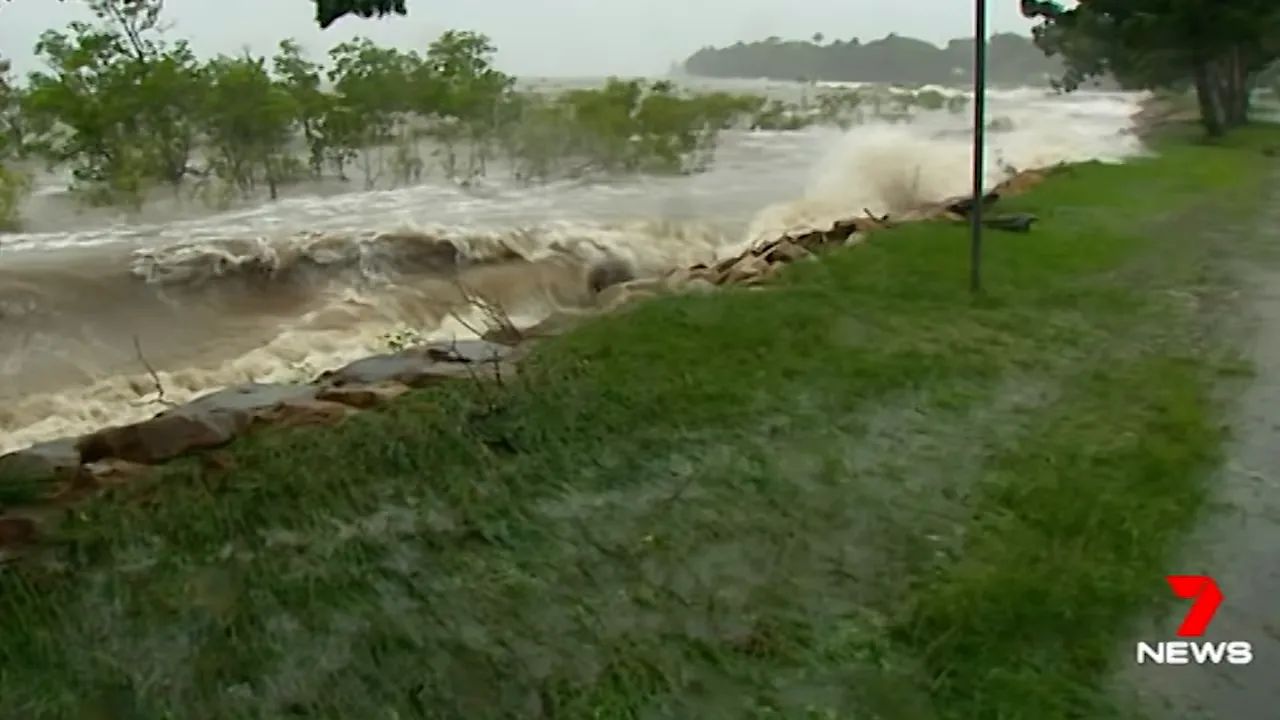 Large waves and storm surge crashing over a shoreline and seawall during a cyclone