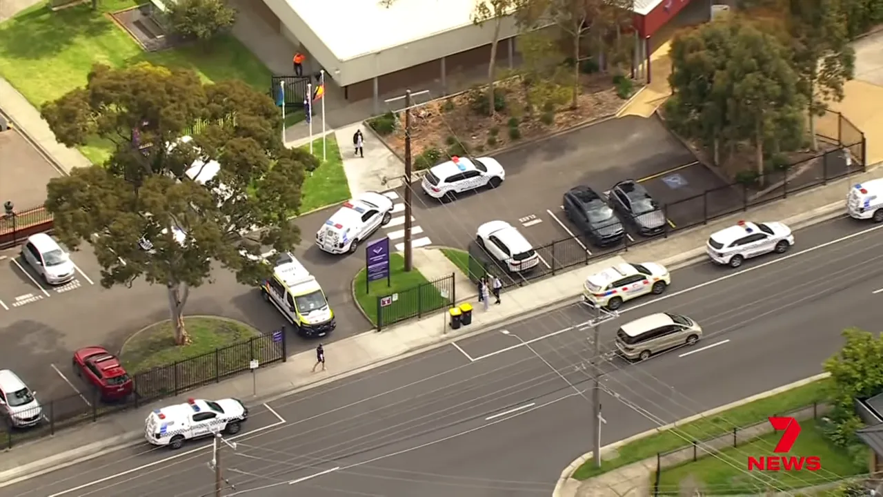 Helicopter/aerial shot showing an ambulance and multiple police vehicles parked outside the gated entrance of Keysborough Secondary College.