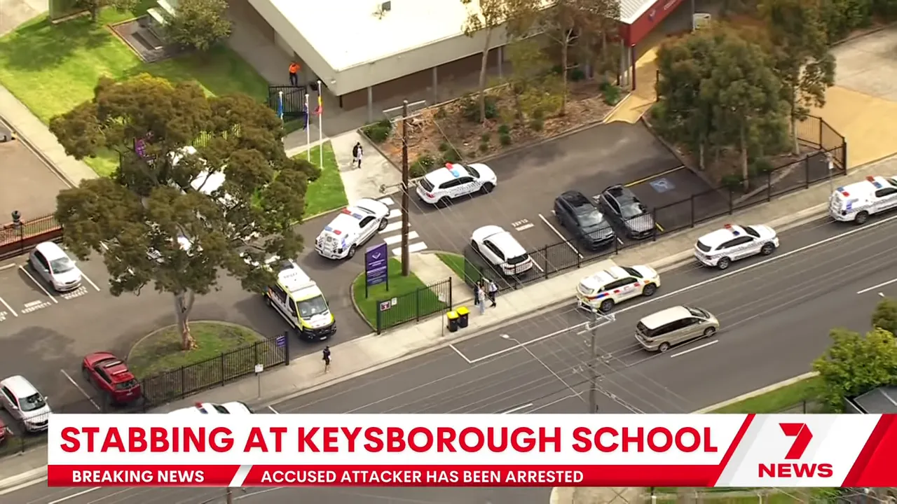 Wide helicopter shot of Keysborough Secondary College entrance with police cars, ambulance and parked vehicles
