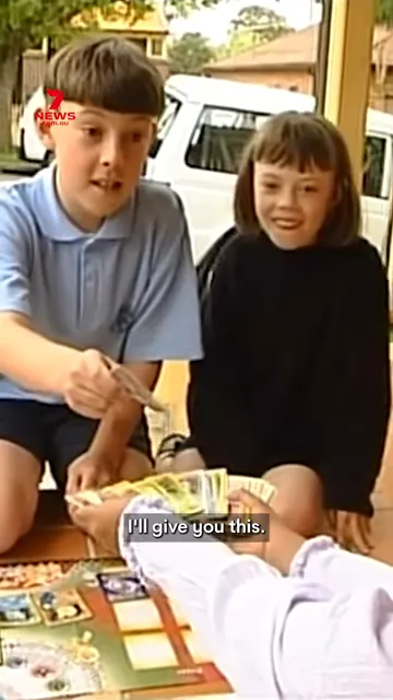 Two children exchanging Pokémon cards and handing over money during a trade.