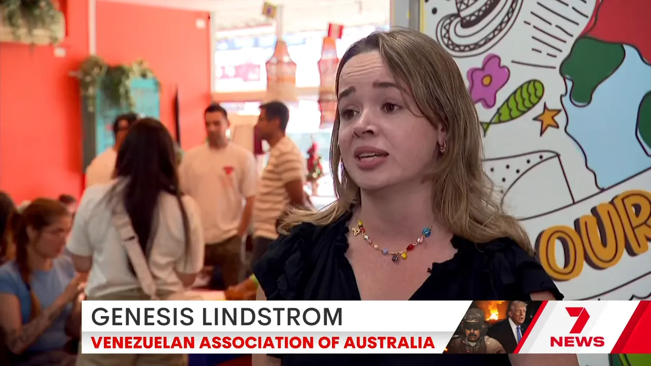 Genesis Lindstrom speaking in an interview, identified on-screen as Venezuelan Association of Australia, with a colourful mural behind her