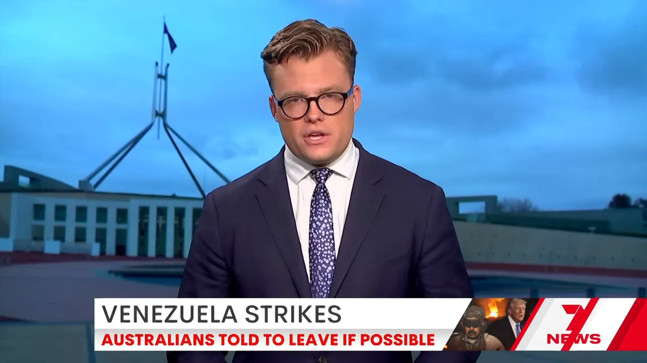 Wide shot of a TV news presenter with chyron: 'Venezuela strikes — Australians told to leave if possible'.