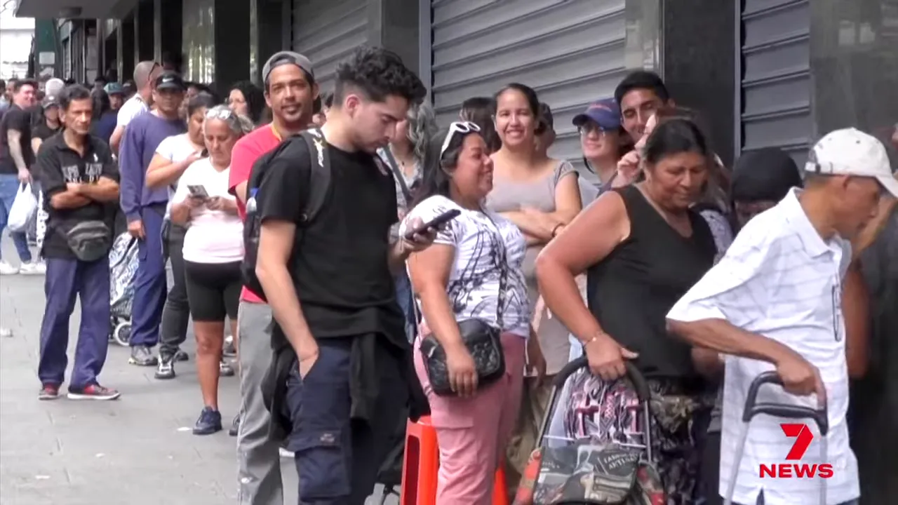 People standing in a long queue outside a shop in Caracas, Venezuela.