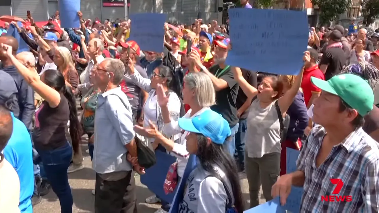 Wide shot of a large crowd in Caracas holding signs and chanting at a street rally