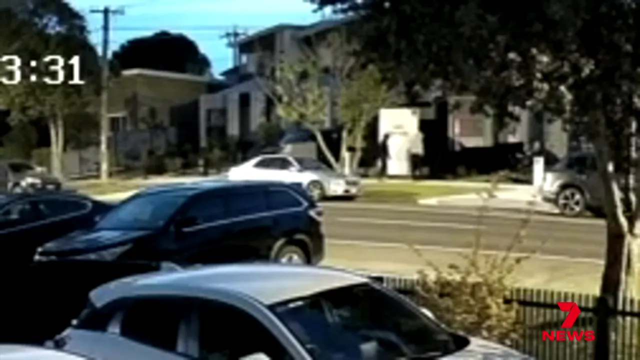 CCTV still showing white car and people near a 'homes for sale' sign outside a house