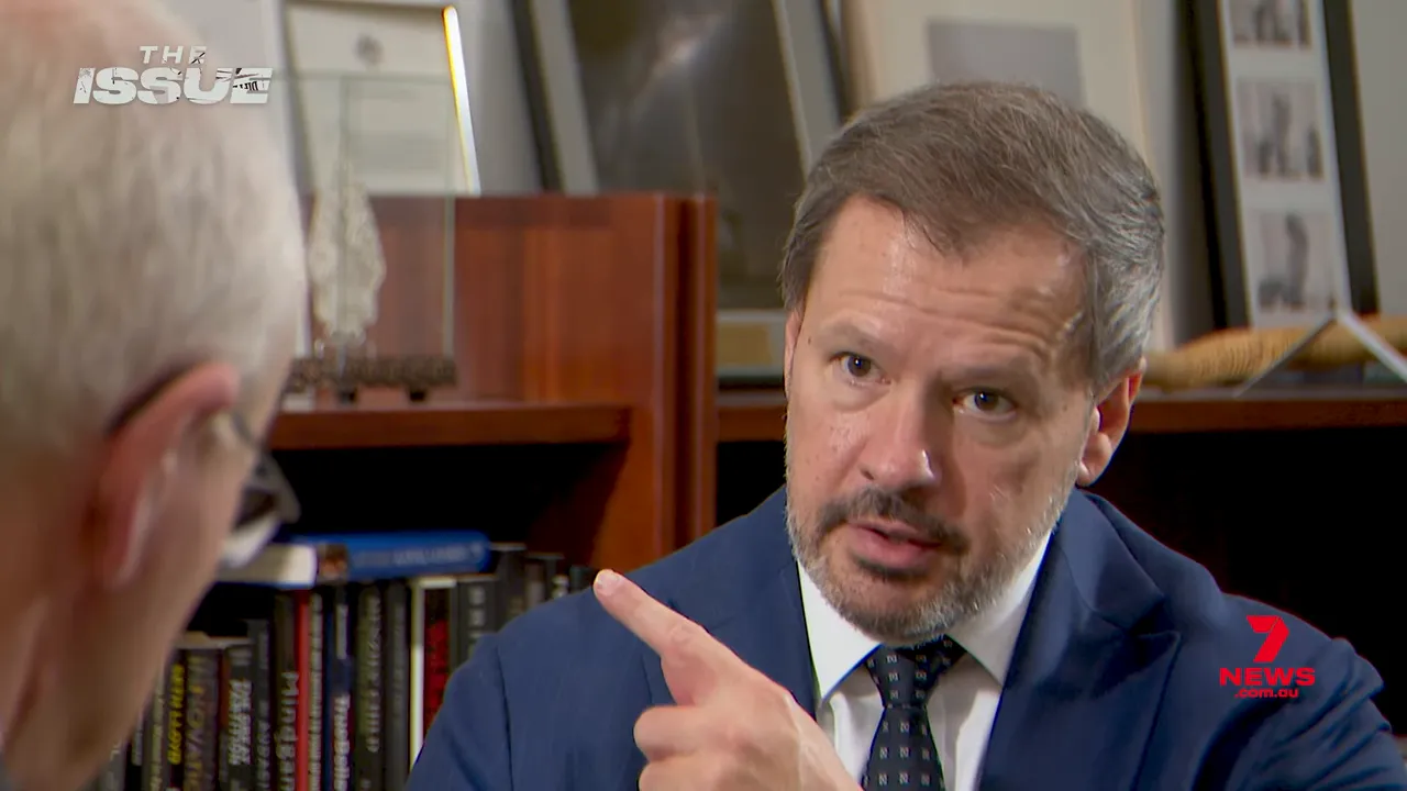 Interview subject pointing during a televised interview, emphasizing a key concern.