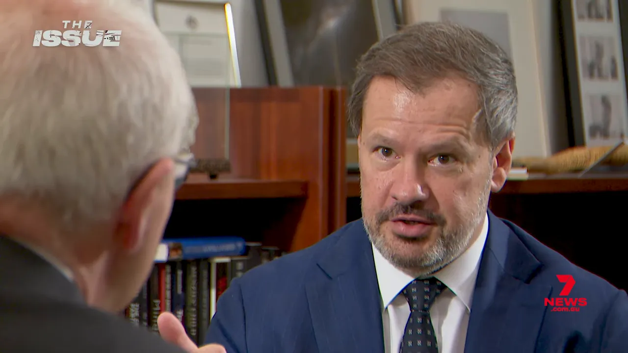 Sharp close‑up of an interview subject speaking in an office, expressing concern about politics and community safety.