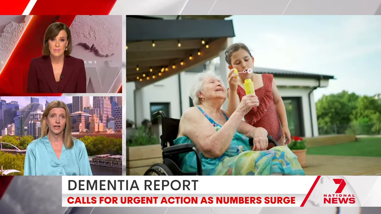 Television news split-screen with anchors at left and a clear, bright shot of a young girl blowing bubbles with an elderly woman in a wheelchair at right.