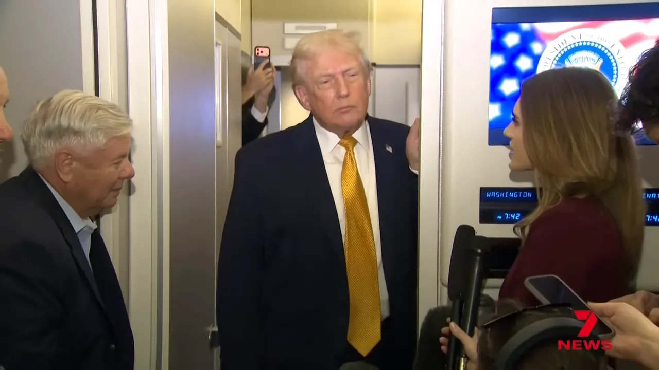 President speaking to reporters on board an aircraft with microphones and display screens visible