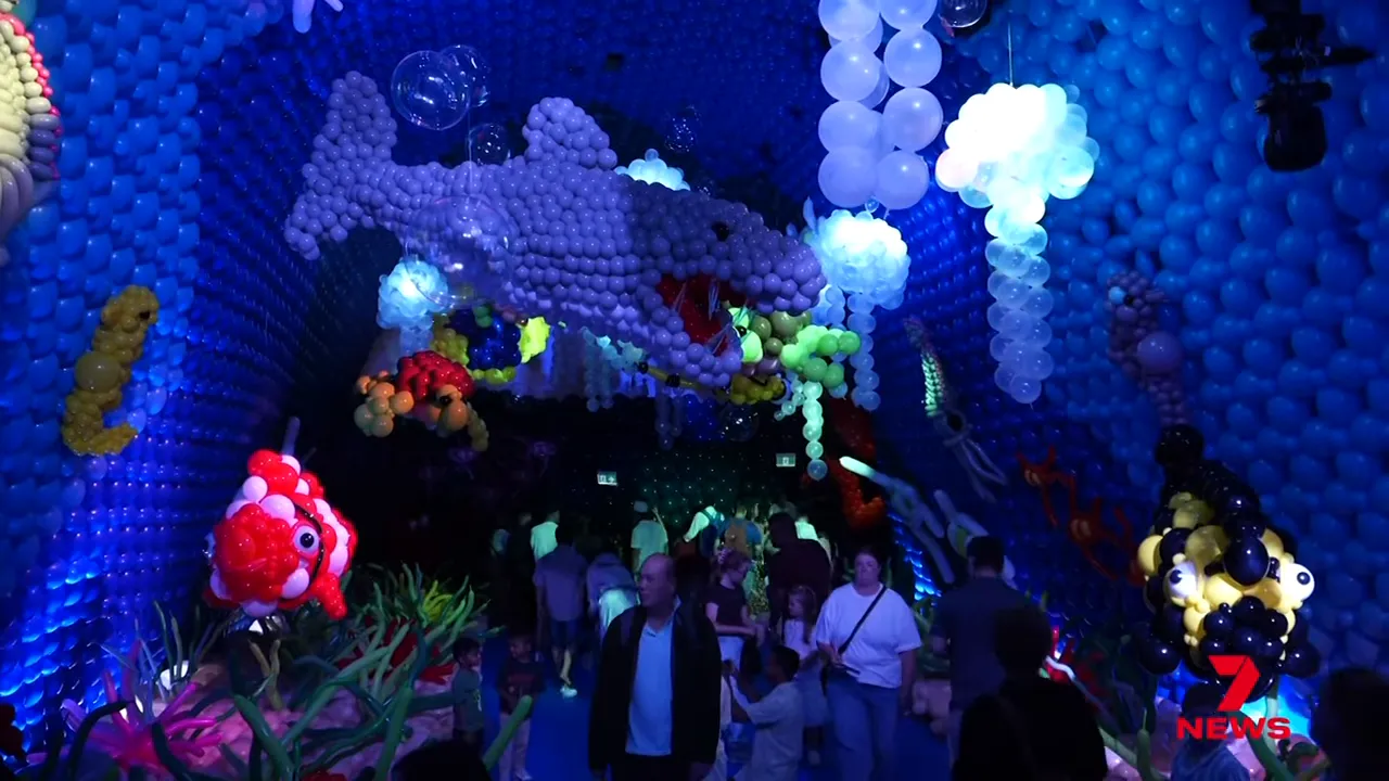 Large underwater-themed balloon installation with suspended shark and visitors
