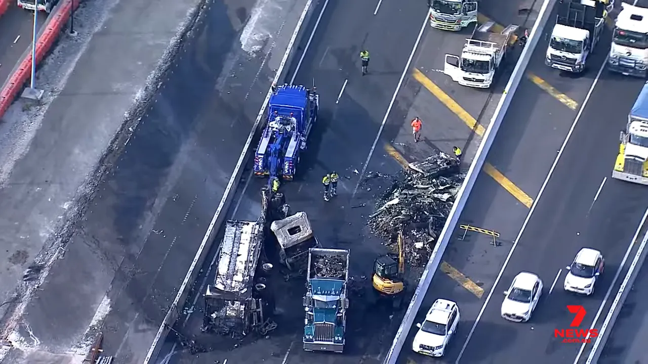 Close aerial view of recovery crews, tow trucks and charred truck debris on motorway lanes