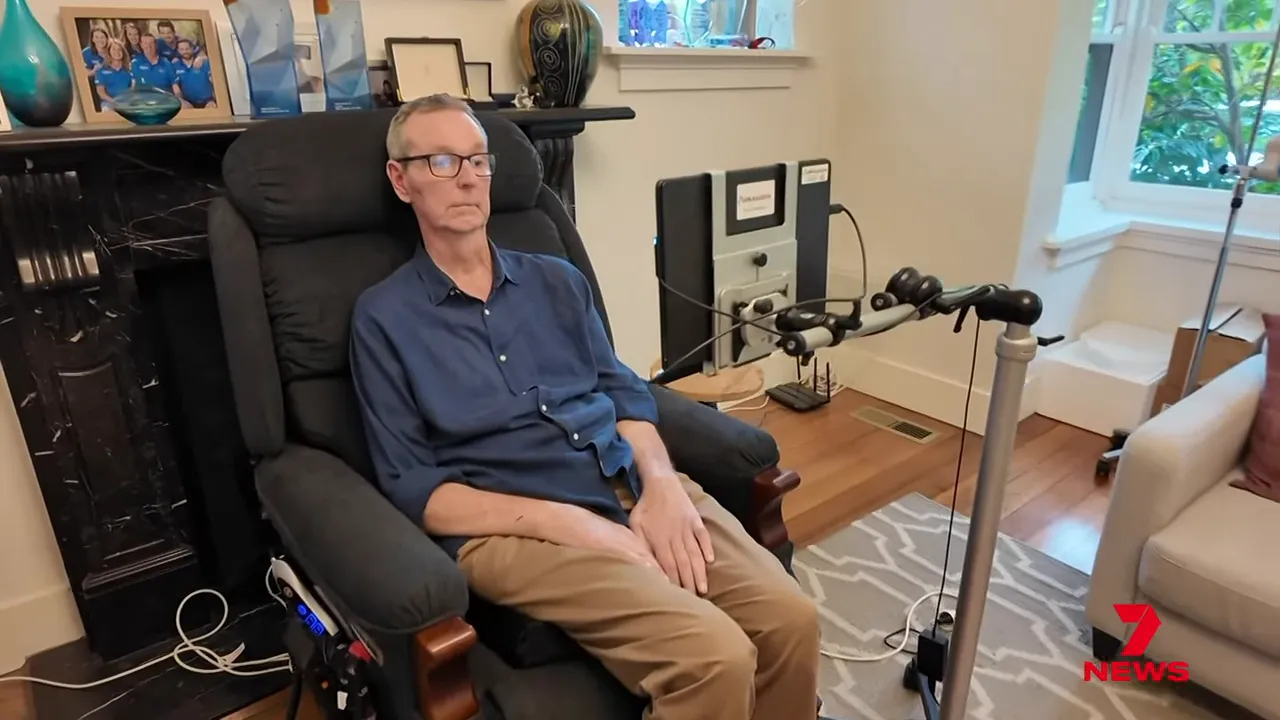 person seated in a recliner using an eye-gaze communication device and monitor in a living room
