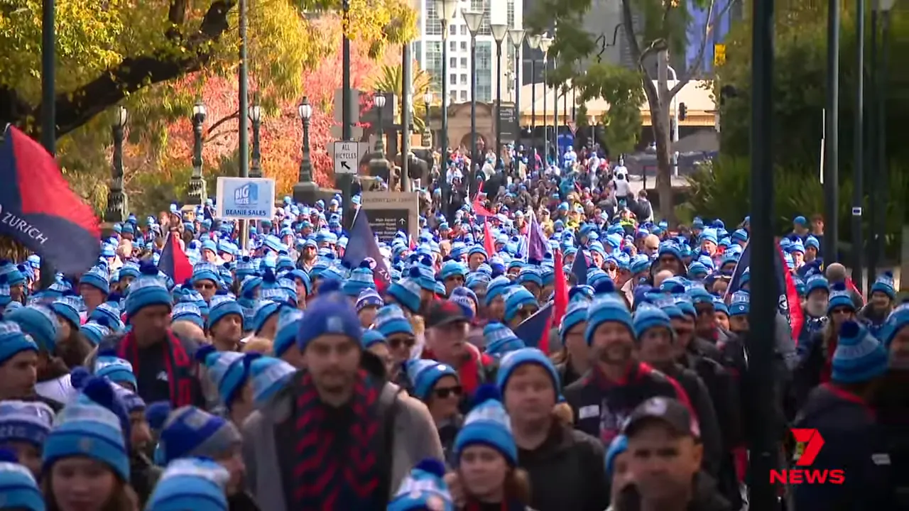 large crowd of people wearing blue beanies at an outdoor fundraising march