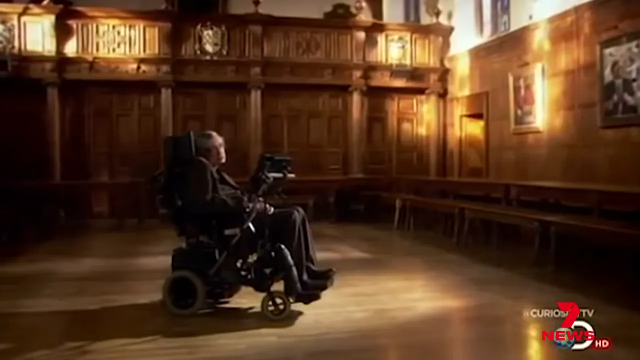 Elderly man in a motorised wheelchair in a wood panelled ceremonial hall, wide shot
