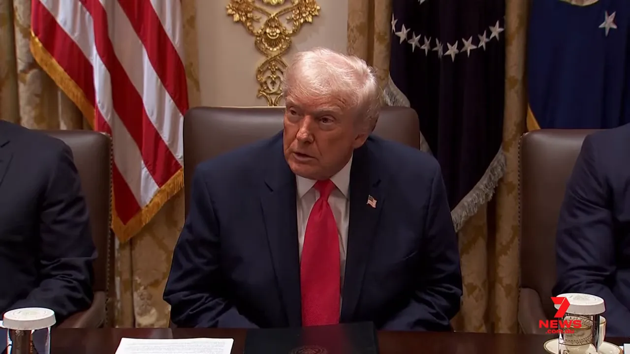 President seated at a conference table during a press meeting, looking up attentively.