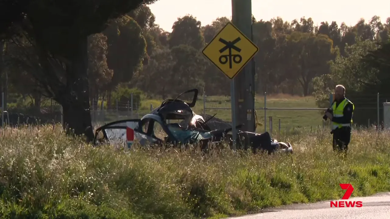daytime shot of a heavily damaged car beside a power pole with an investigator at the scene