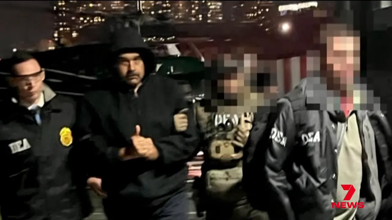Man giving a thumbs-up while being escorted by law enforcement officers outside a vehicle; several officers' faces are pixelated.