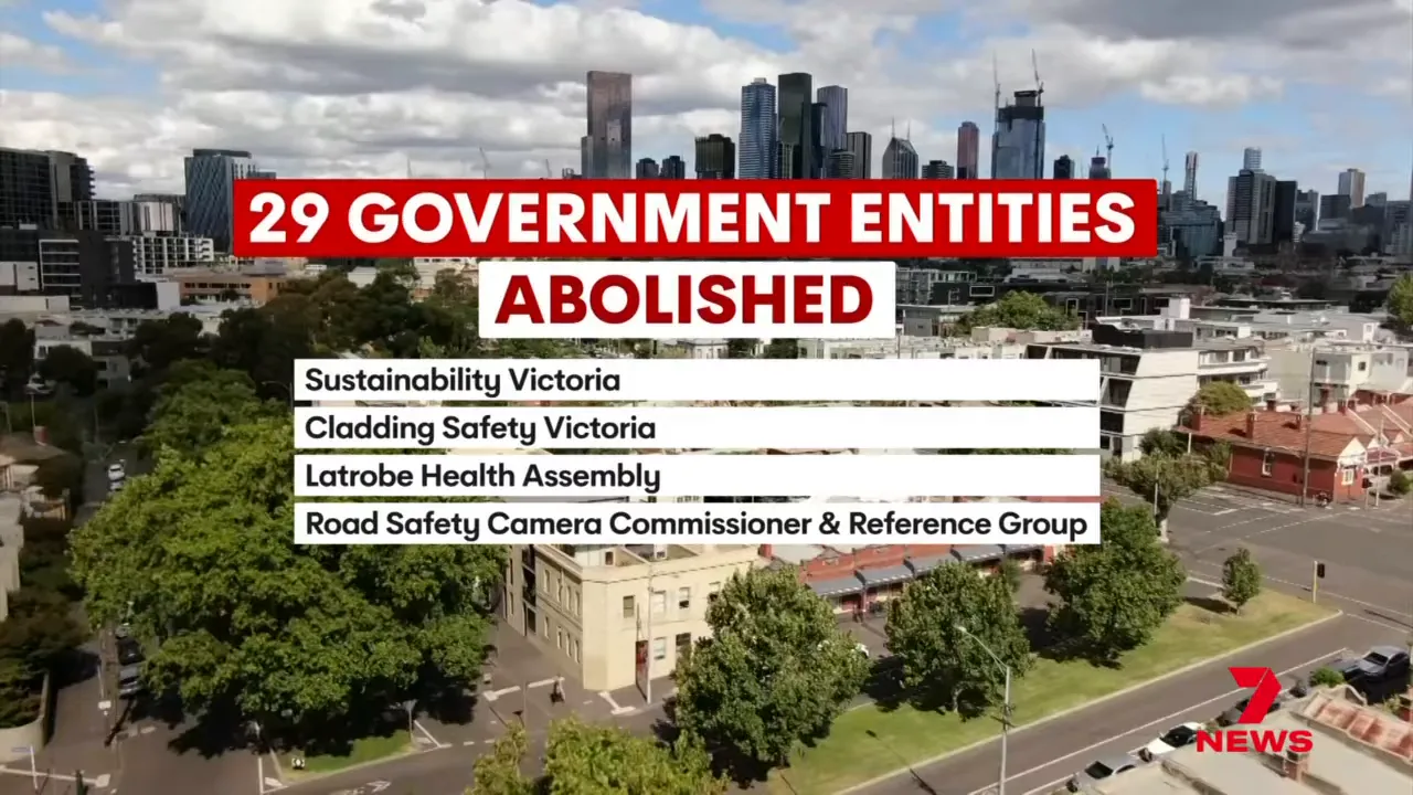 On-screen graphic reading '29 Government Entities Abolished' over an aerial city view with a short list including Sustainability Victoria and Latrobe Health Assembly.