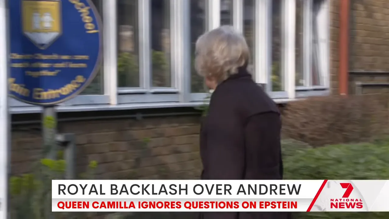 Queen Camilla walking past a school sign and windows during a visit