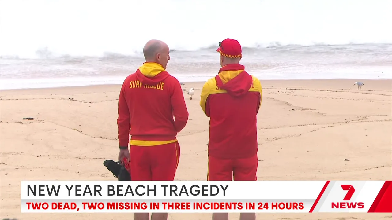 Two surf lifesavers in red and yellow uniforms standing on a Sydney beach looking out to the ocean