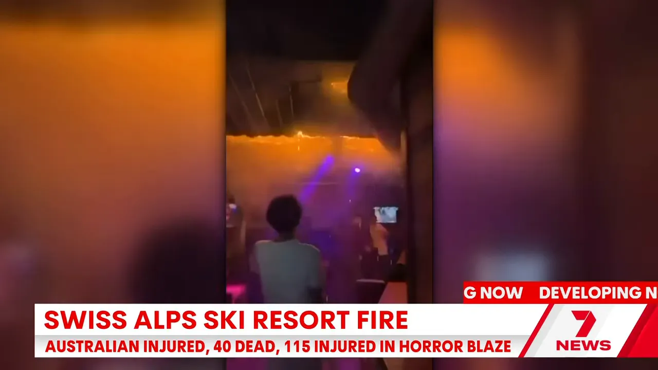 Interior shot of a bar with smoke and flames along the ceiling, patrons standing and filming on phones as purple lighting shows through the haze.