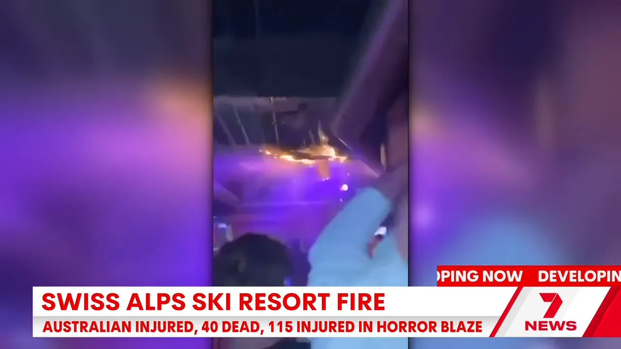 Vertical video still from inside the venue showing bright flames along the ceiling, purple lighting and patrons raising phones during the fire.