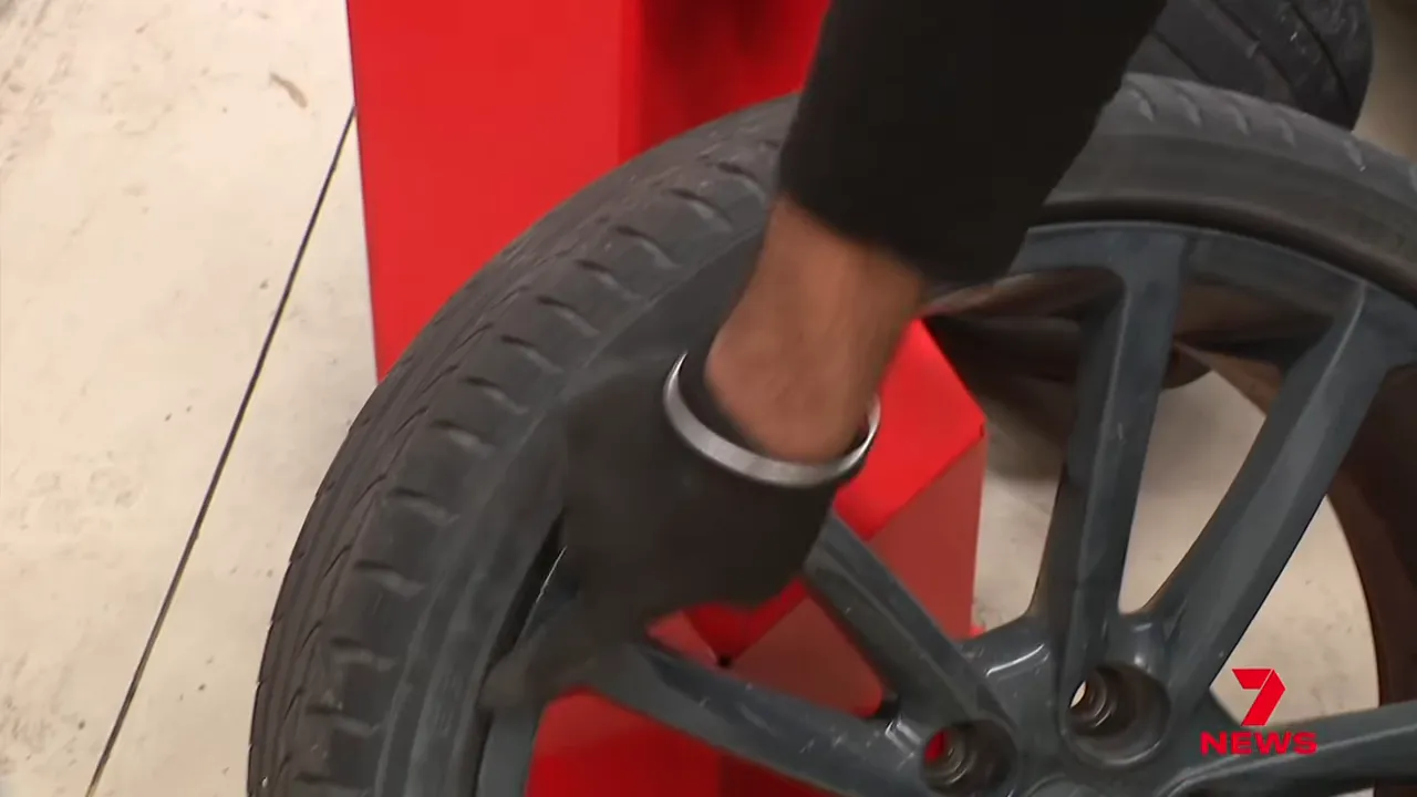 Mechanics inspecting damaged car wheel