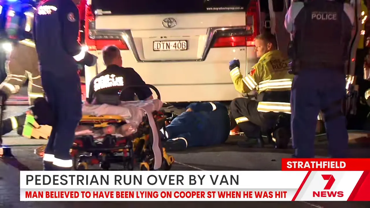 Paramedics attending injured man next to van at Strathfield Cooper Street incident