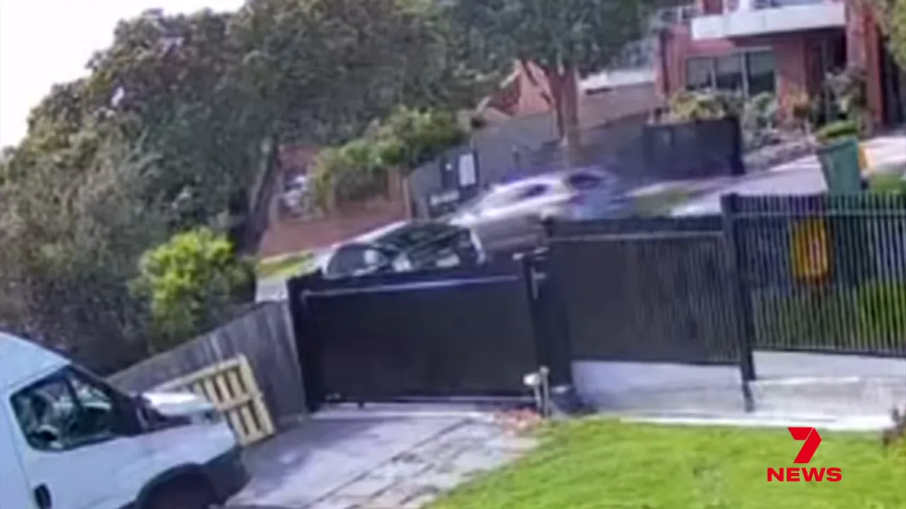 CCTV image of a car travelling past a residential gate on a suburban street