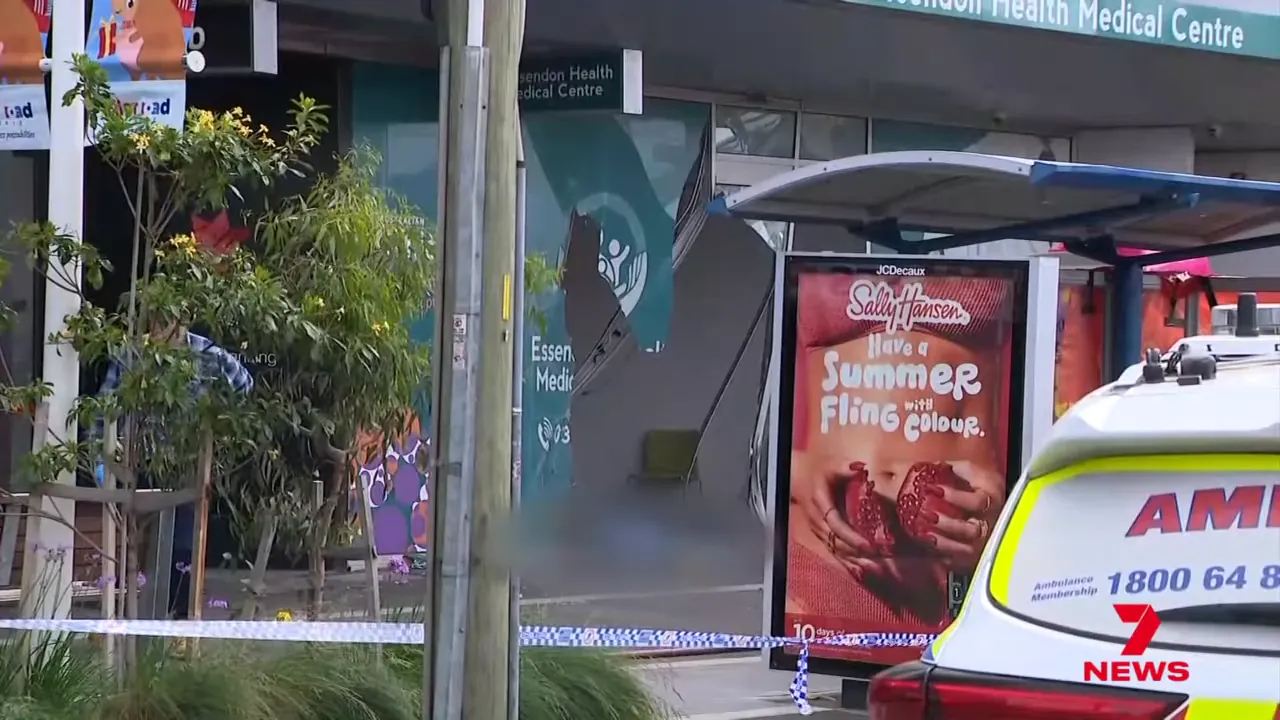 Front entrance of the medical centre with smashed glass and an ambulance parked outside