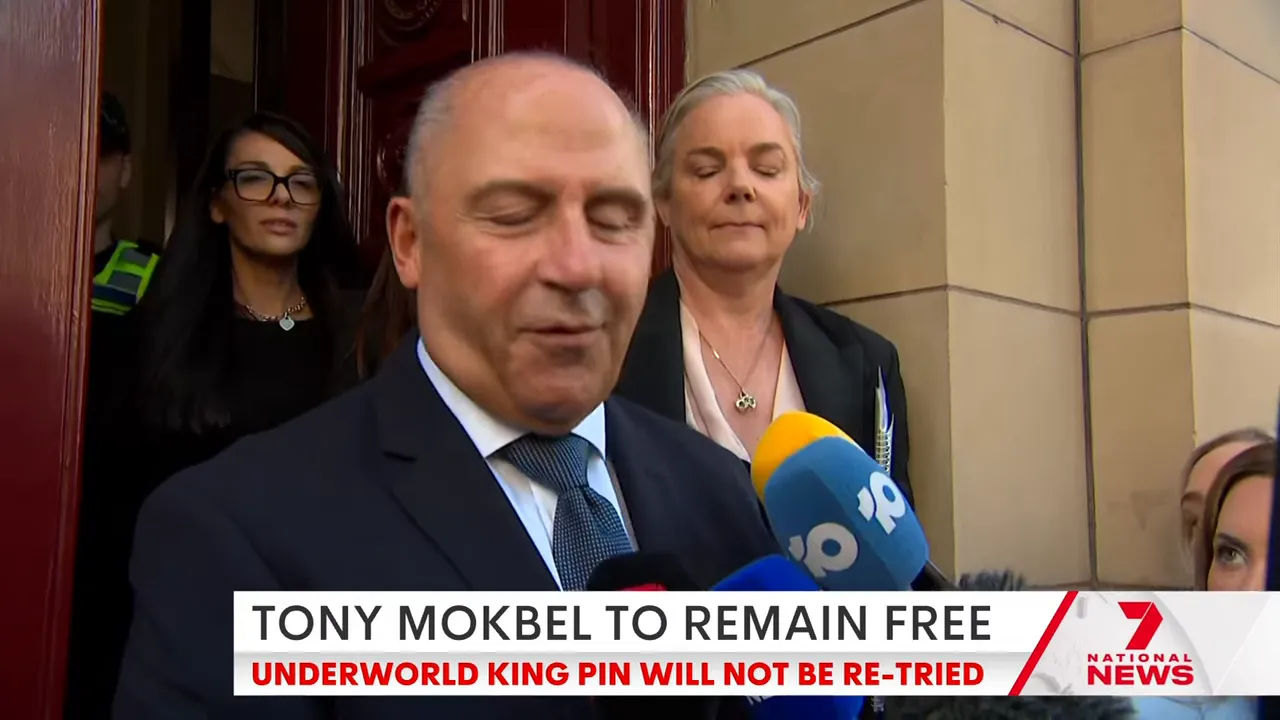 Man giving a statement to reporters at the courthouse steps with multiple microphones in view