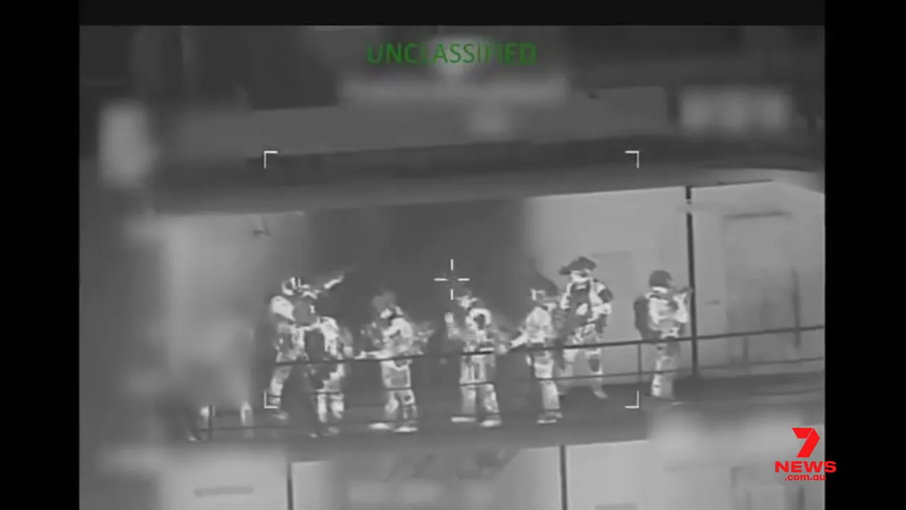 Infrared/thermal image of a line of boarding personnel on a tanker deck with targeting reticle