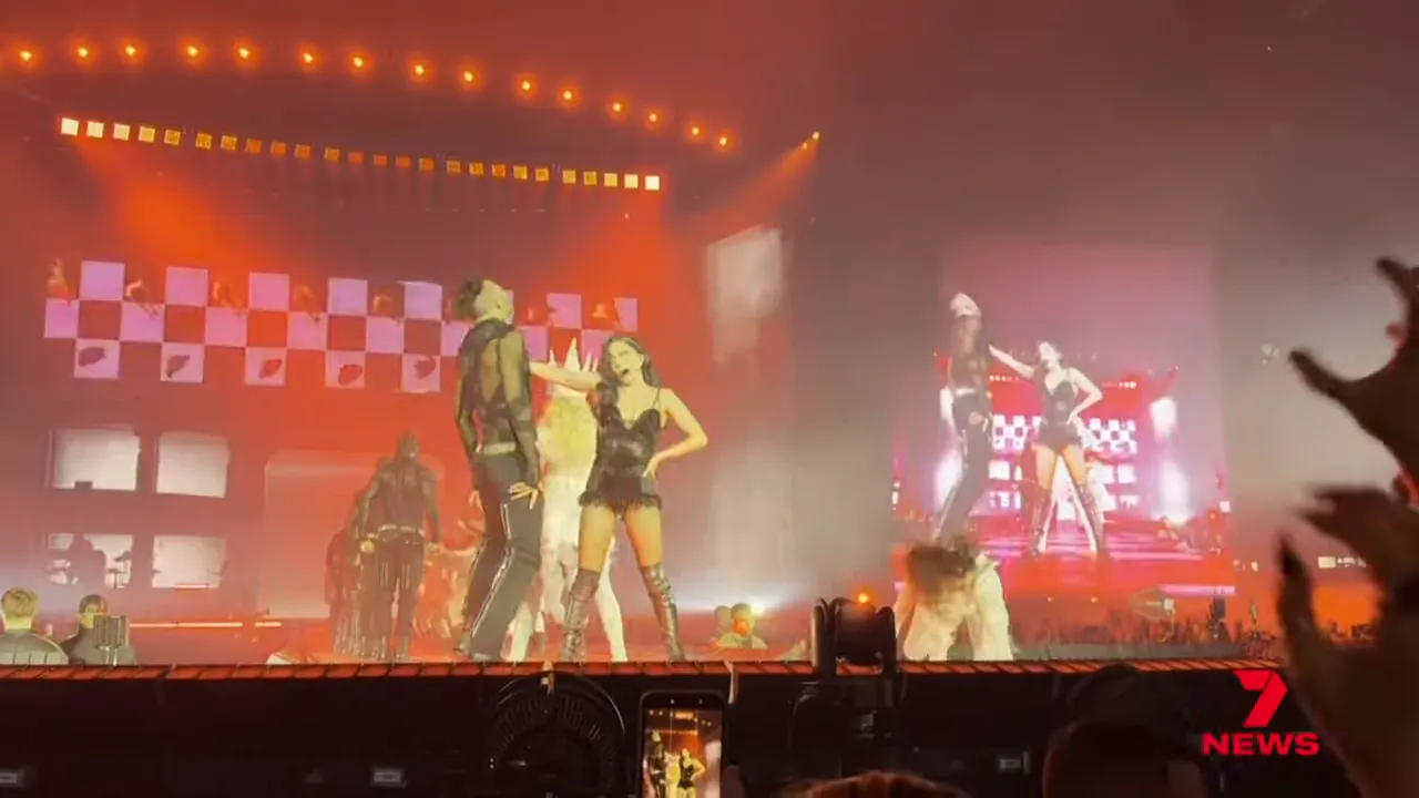 Wide view of the main stage showing performers, dancers and a large video screen with theatrical lighting