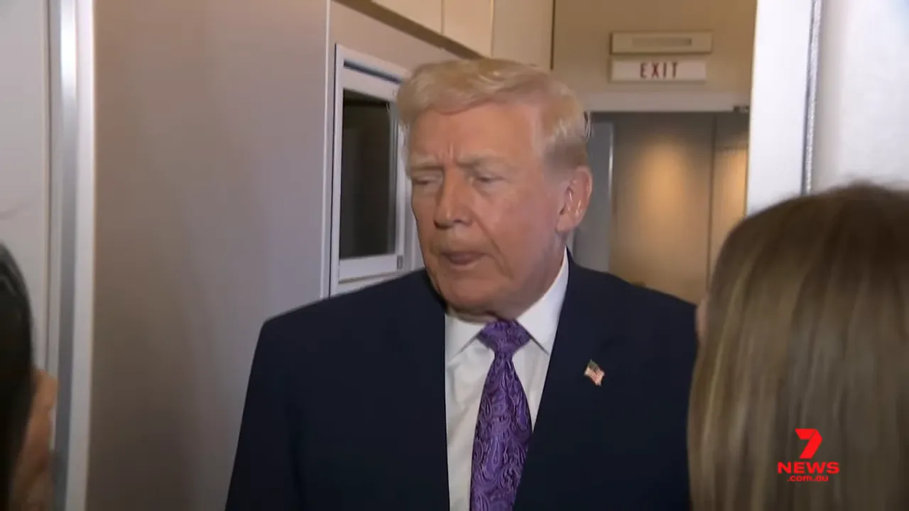 Man in a suit standing in an aircraft doorway with reporters at the edges, looking downcast