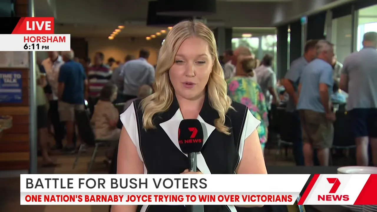 Female field reporter holding a 7 News microphone inside a crowded Horsham hall with on-screen banner 'Battle for bush voters' and 7 News branding