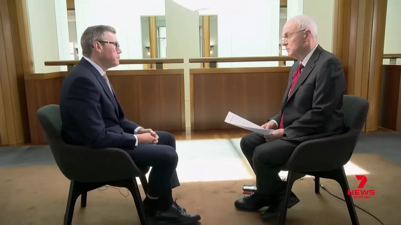 Wide shot of a two-person sit-down interview discussing AUKUS and submarine delivery challenges