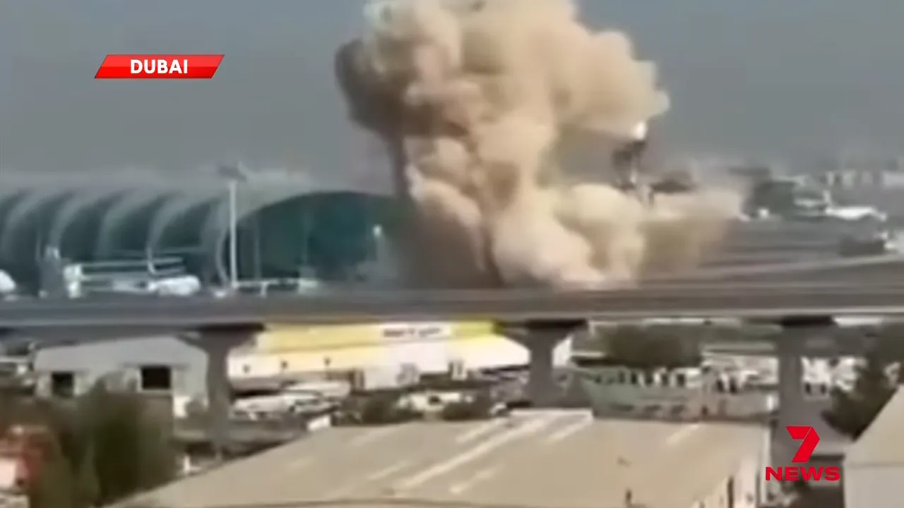 Close view of large smoke cloud rising beside Dubai International terminal with elevated road in foreground