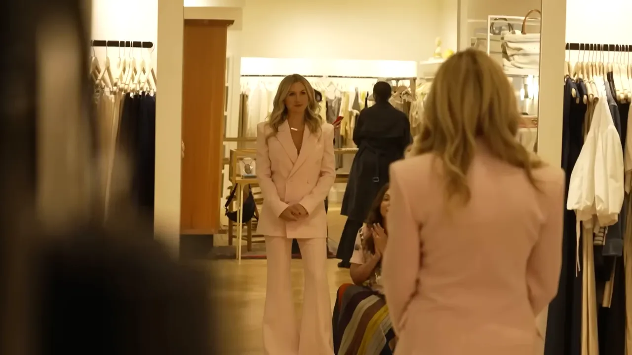 Shelton trying on a designer pink suit in a luxury boutique
