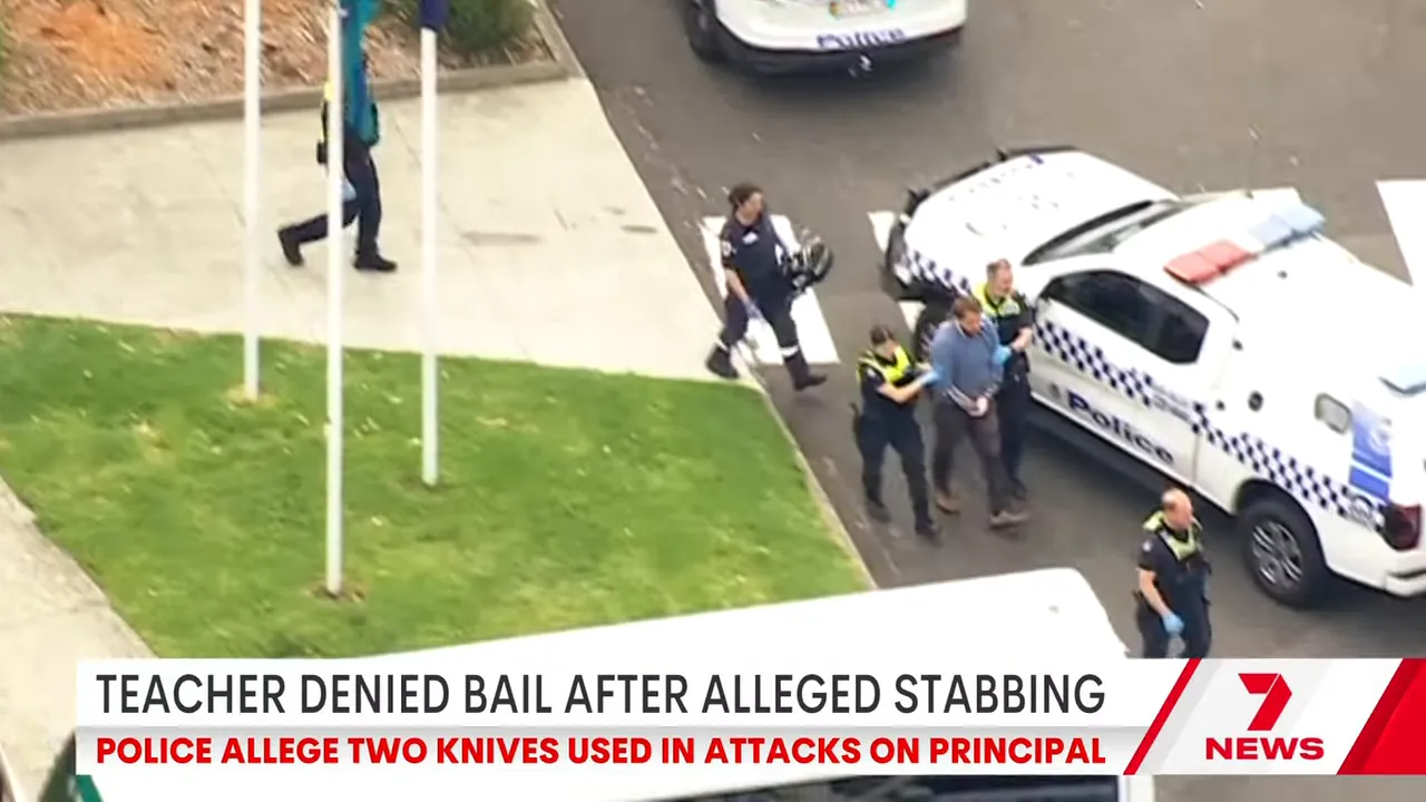 Police officers escorting a handcuffed man toward a police vehicle at the school carpark