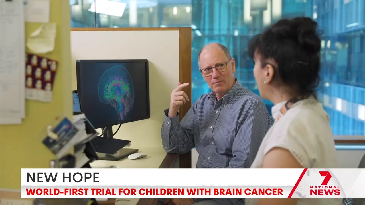Clinician and researcher talking beside a computer displaying a coloured brain scan in a hospital office