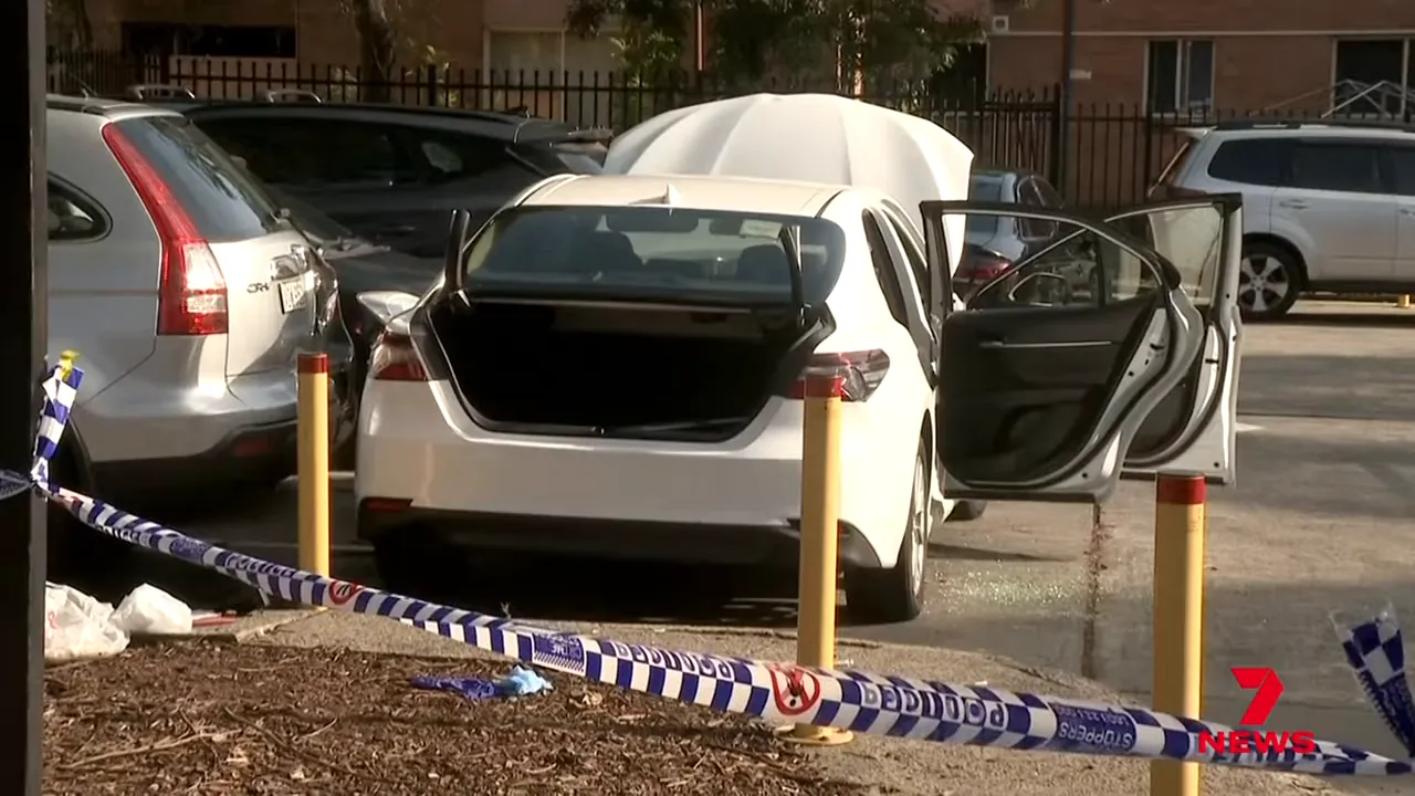 White Toyota Camry with trunk open and police tape at a cordoned crime scene