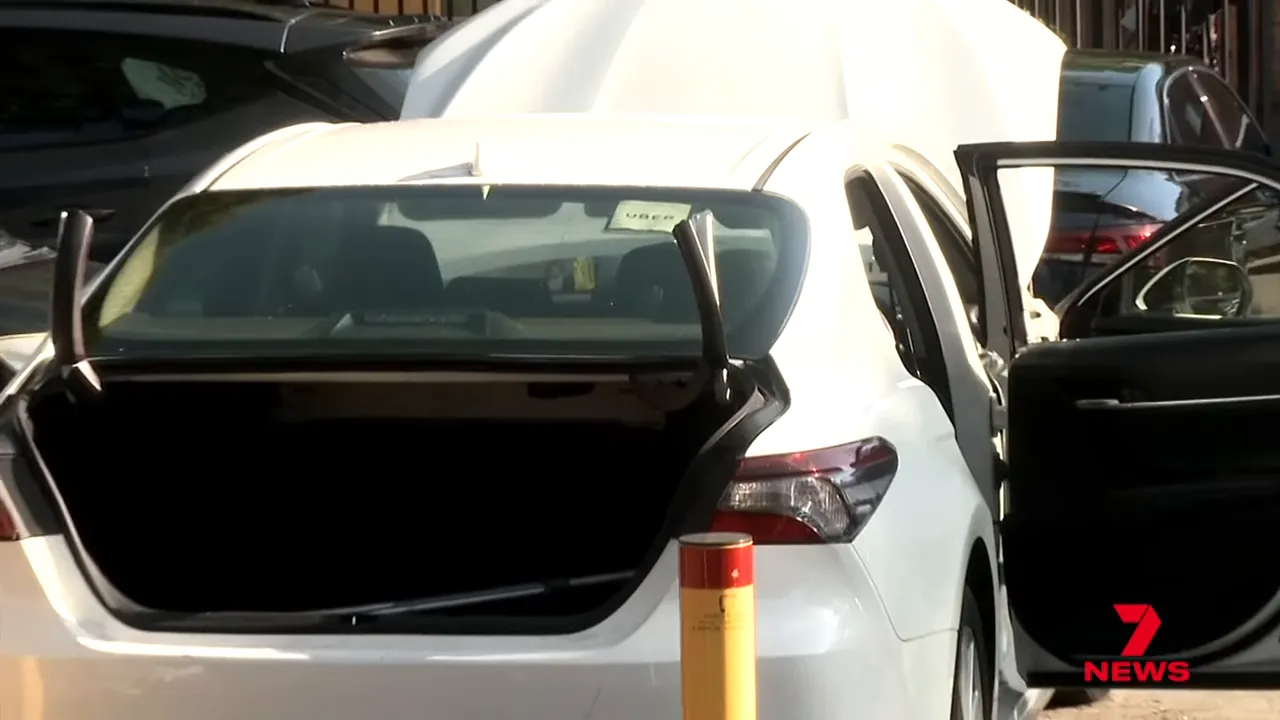 White Toyota Camry with open boot and rear passenger door, Uber sticker visible on windscreen